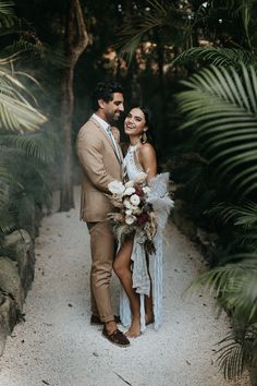 a bride and groom standing in the middle of a path surrounded by palm trees at their wedding