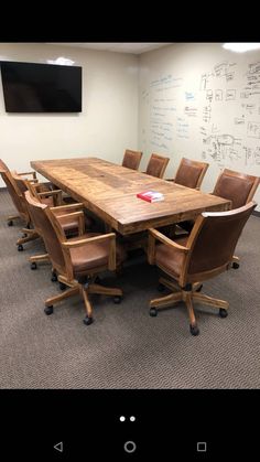 an office board room with a large wooden table surrounded by brown leather chairs and writing on the wall