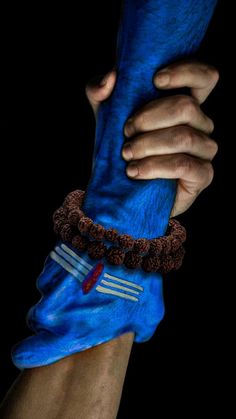 two hands holding something in the dark with blue cloth on it's wrist and bracelet