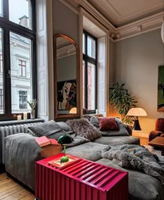 a living room filled with lots of furniture next to large windows on top of a hard wood floor