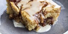 two pieces of cinnamon roll with icing on a blue and white plate, sitting on a table