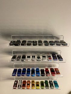 a wall mounted display case filled with lots of different colored cars on it's sides