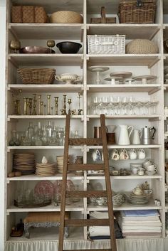 a ladder is in front of shelves with dishes and other items