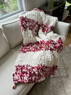 a crocheted blanket sitting on top of a white couch next to a window