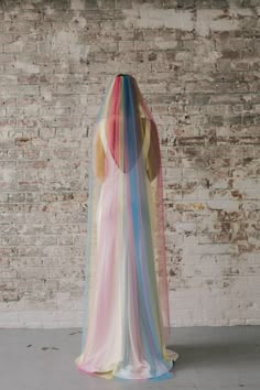 the back of a woman's dress with multicolored fabric draped over it