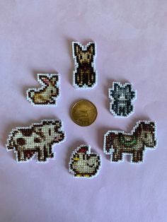 six small beaded animal magnets sitting next to a penny on a pink surface