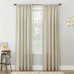 a living room with white curtains and a rug in front of the window on top of a hard wood floor