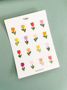 the tulips sticker sheet is on top of a green surface and there are other flowers