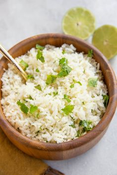 a wooden bowl filled with white rice and garnished with cilantro leaves