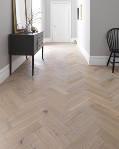 an empty room with wood floors and a mirror on the wall, next to a black chair