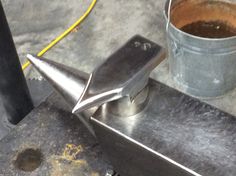 a metal object sitting on top of a table next to a cup with liquid in it