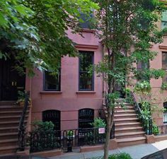 an apartment building with stairs leading up to the front door and trees on either side