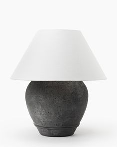 a gray vase with a white shade on it's side and a light in the middle