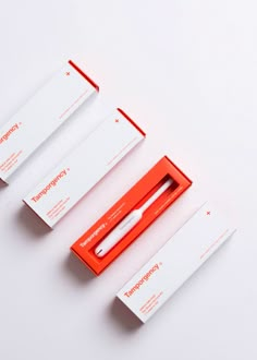 three red and white boxes with pens in them