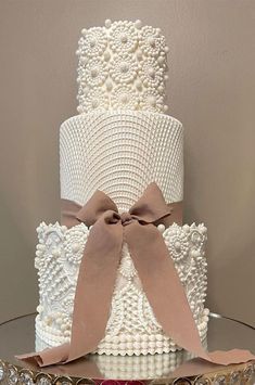 a three tiered wedding cake decorated with pearls and bows