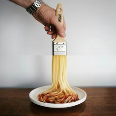 a person is holding a wooden spatula with spaghetti in it on a white plate