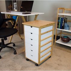 a computer desk with a laptop on top of it next to a book shelf and chair