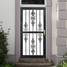 a black and white front door with wrought iron bars on the top, next to some bushes