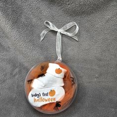 a glass ornament with a baby's first halloween design