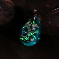 a green and white necklace with glow in the dark leaves on it's side