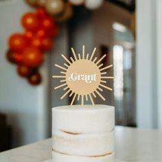 a white cake topped with a frosted sun on top of a table