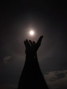 a person's hand reaching up to the sky with the moon in the background