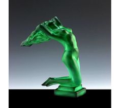 a green sculpture is sitting on a black surface and it appears to be in the shape of a woman's body