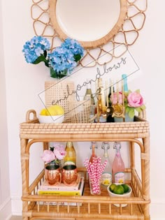 a wicker bar cart with flowers and drinks on it in front of a mirror