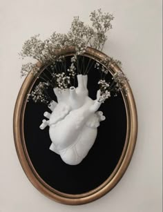 a heart shaped vase with baby's breath in front of a black and gold mirror