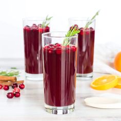 two glasses filled with cranberry juice and garnished with fresh herbs on the rim