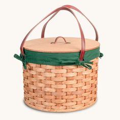 a large woven basket with green linings on the bottom and brown leather straps around it