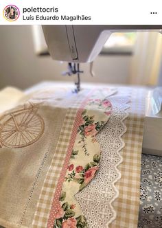 the sewing machine is on top of the table next to the lace and flowery fabric