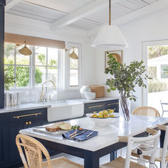 a kitchen with blue cabinets, white counter tops and an island in front of the sink