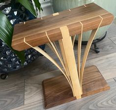 a wooden bench sitting on top of a hard wood floor next to a potted plant