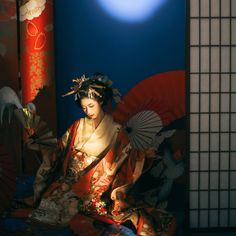 a geisha woman sitting on the ground with an umbrella