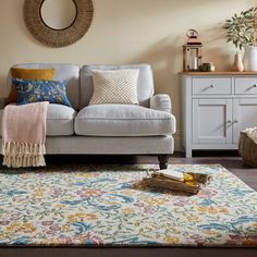 a living room filled with furniture and pillows on top of a rug in front of a window