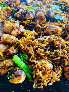 chicken and noodle stir fry on a black plate