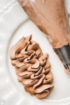 a white plate topped with chocolate frosting next to a pastry bag and an umbrella