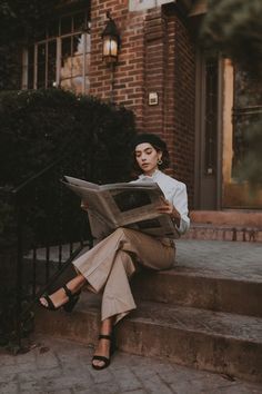 a woman sitting on steps reading a newspaper