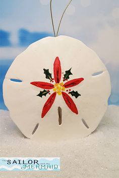 a white sand dollar with a red flower painted on it