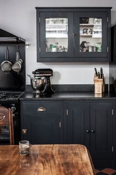 a kitchen with black cabinets and wooden table