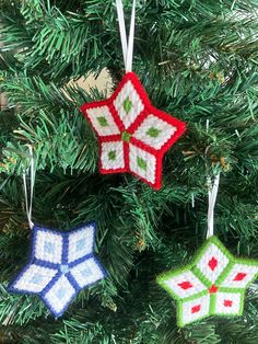 three crocheted christmas ornaments hanging from a green tree with red and white snowflakes