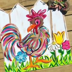 a painting of a rooster on a fence with flowers and a bow in the background