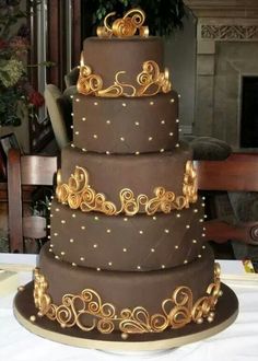 a three tiered chocolate cake with gold decorations