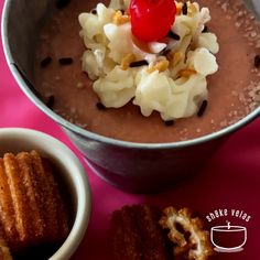 a bowl filled with chocolate pudding next to other desserts on a pink table cloth