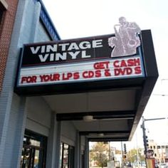 an old theater sign on the side of a building that says vintage vinyl get cash for your cd's & dvd's