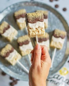 a hand holding a marshmallow bar on a stick