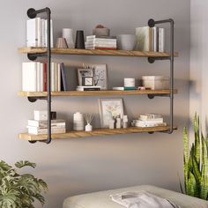 three shelves with books, candles and other items on them in a living room area