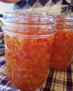 three jars filled with food sitting on top of a checkered tablecloth covered table