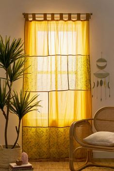 a living room with a chair, potted plant and yellow curtains